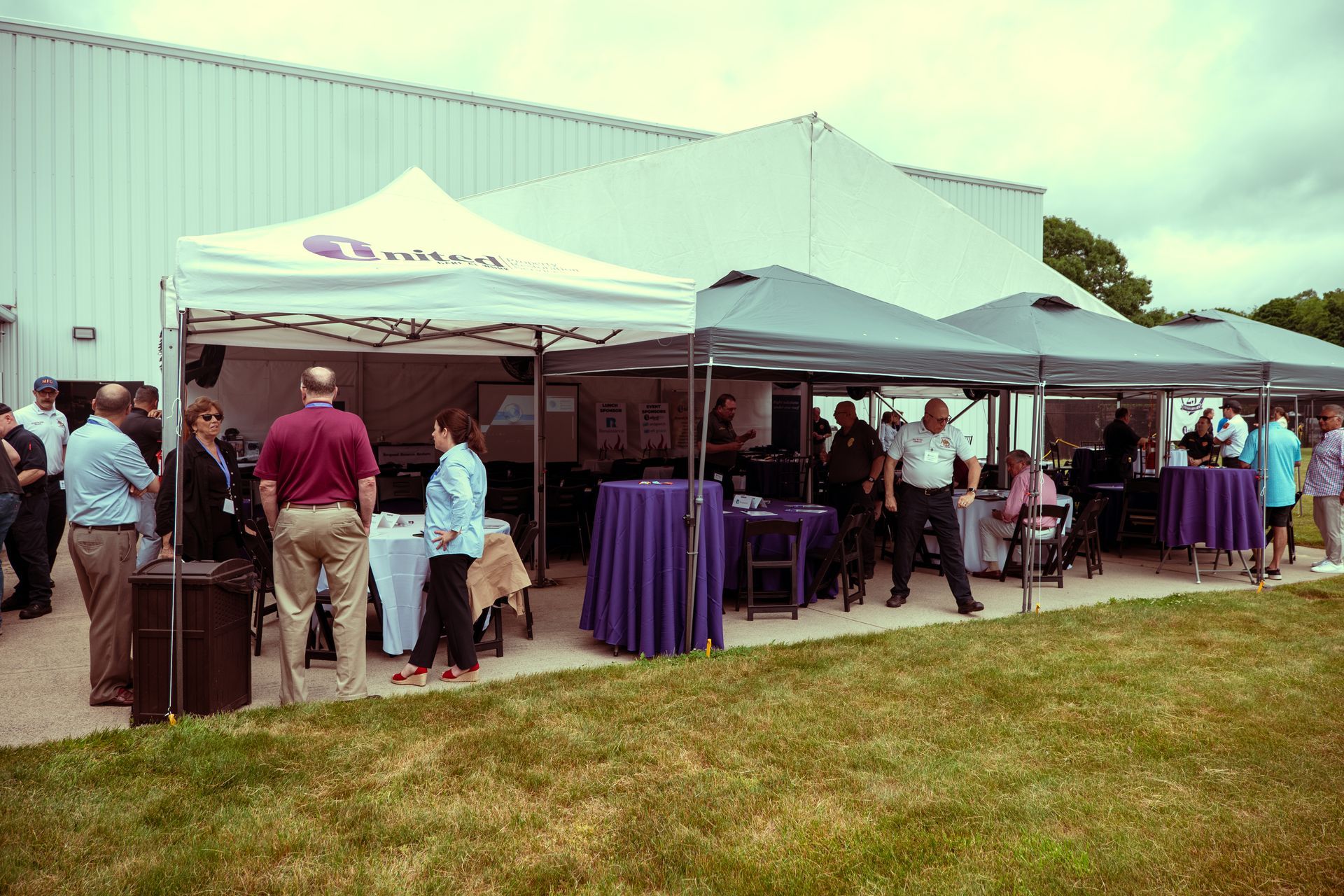 A group of people are standing under tents in front of a building.