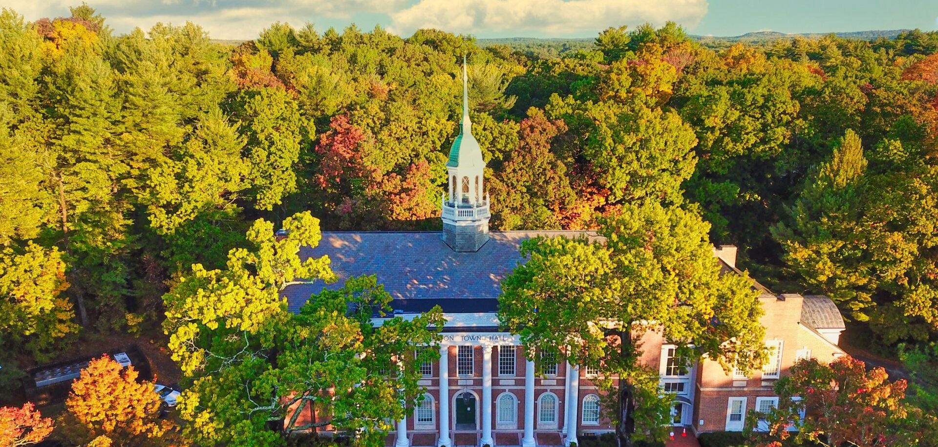 An aerial view of a church surrounded by trees in the middle of a forest.