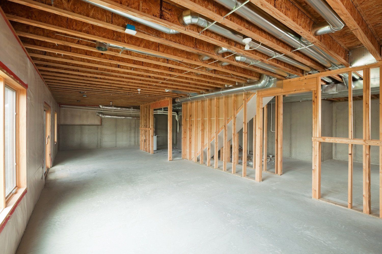 An empty basement under construction with wooden beams and a staircase.