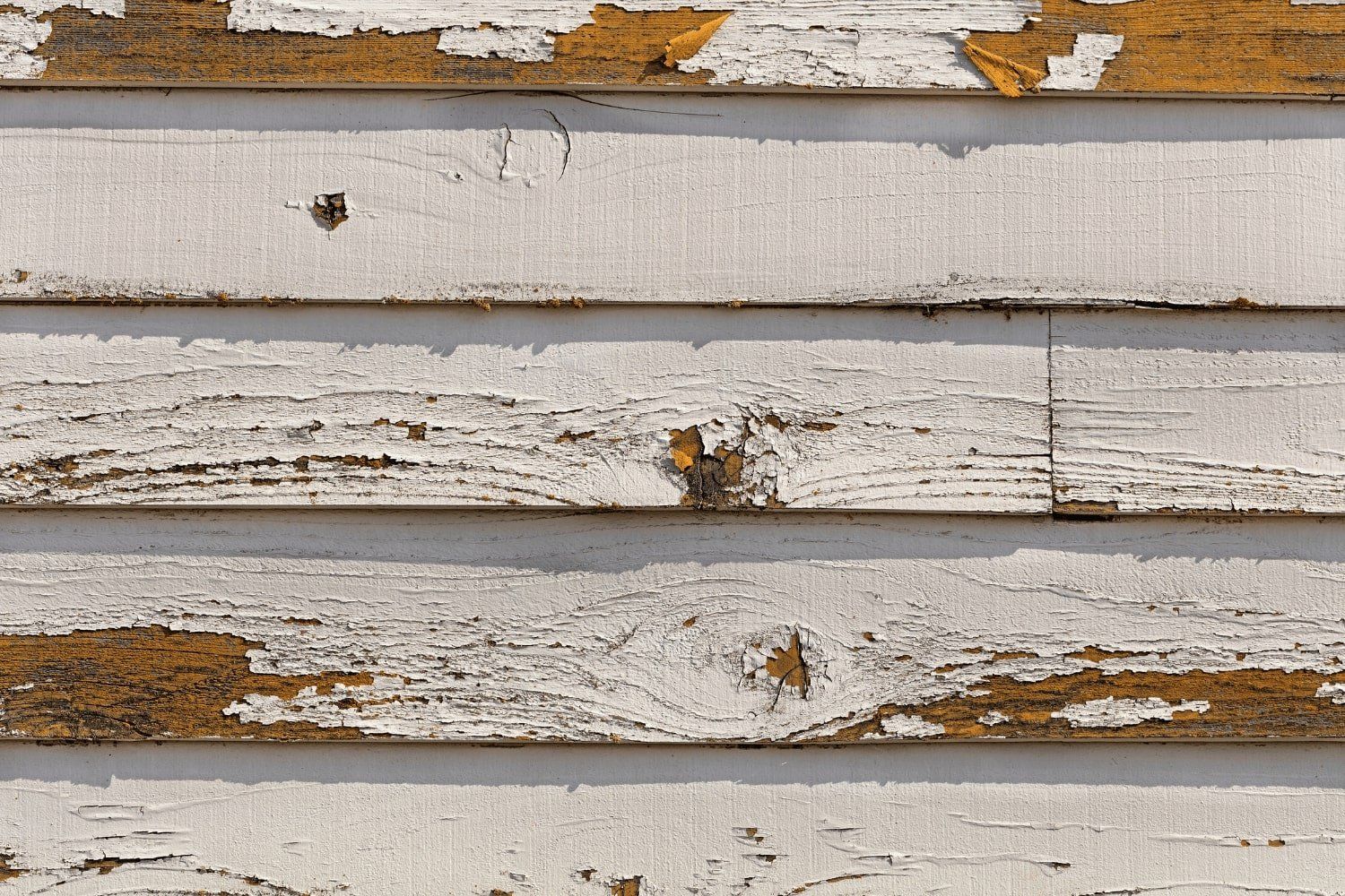 A close up of a white wooden wall with peeling paint