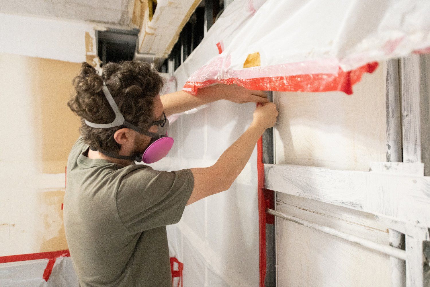 A man wearing a mask is working on a wall.