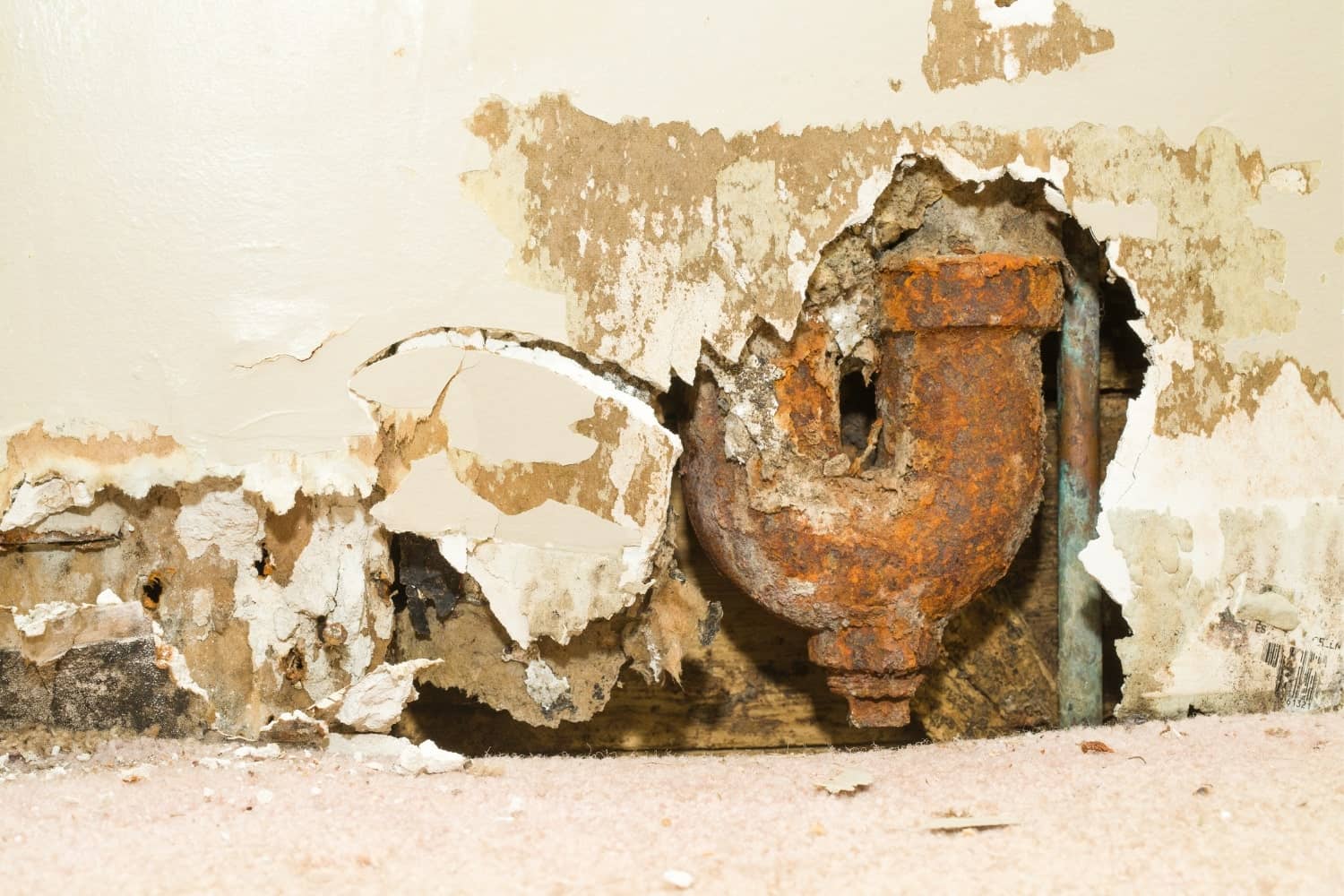 A rusty pipe is sticking out of a hole in a wall.