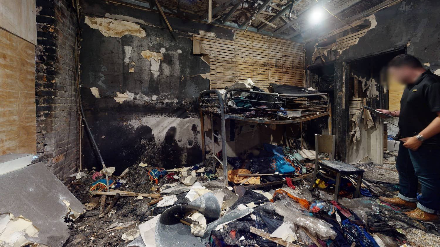 A man is standing in a room with a lot of trash in it.