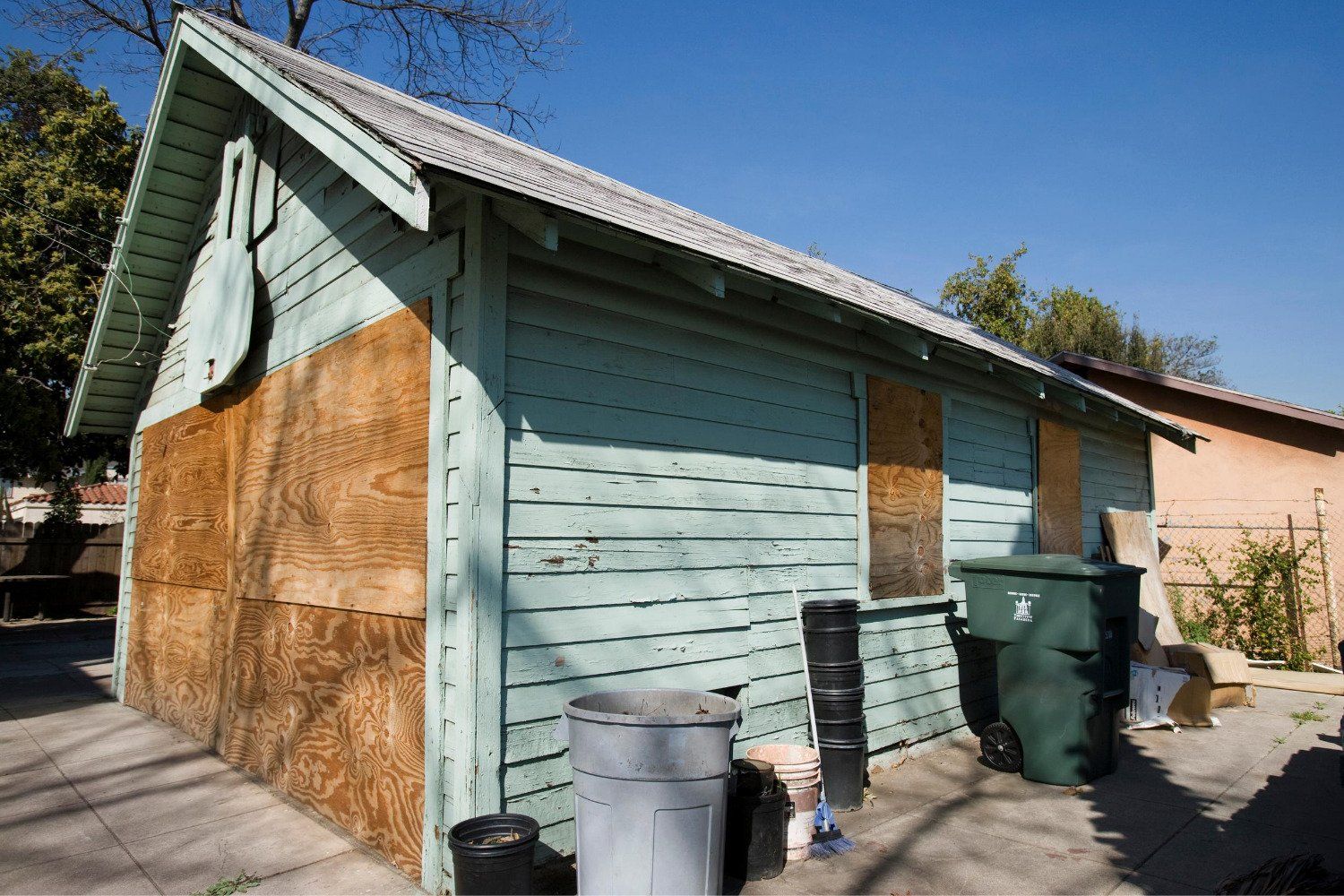A small house with a green trash can in front of it