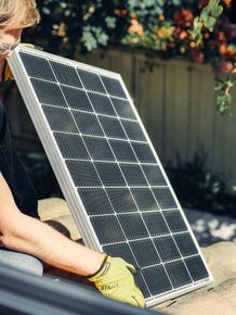 A man is holding a solar panel in his hands.