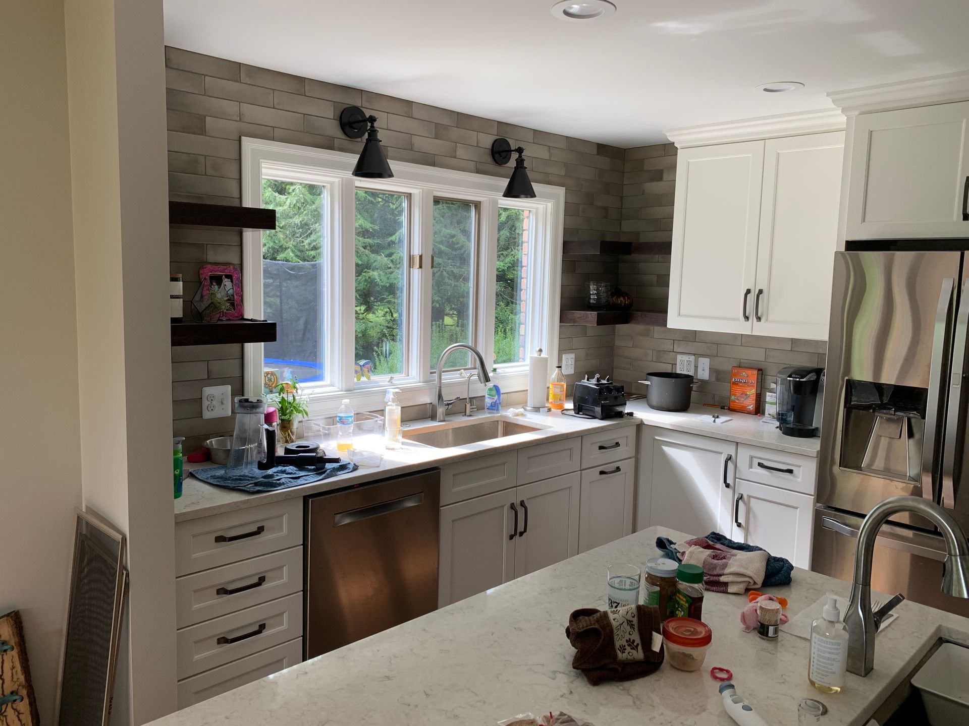 A kitchen with white cabinets , stainless steel appliances , a sink , and a refrigerator.
