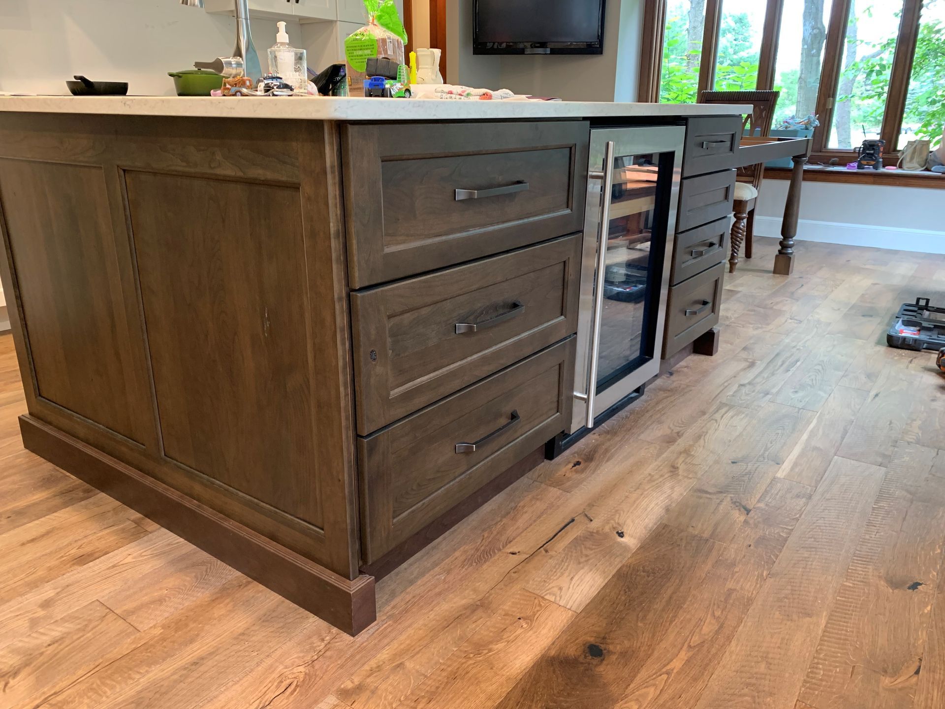 A kitchen with a large island with drawers and a refrigerator.