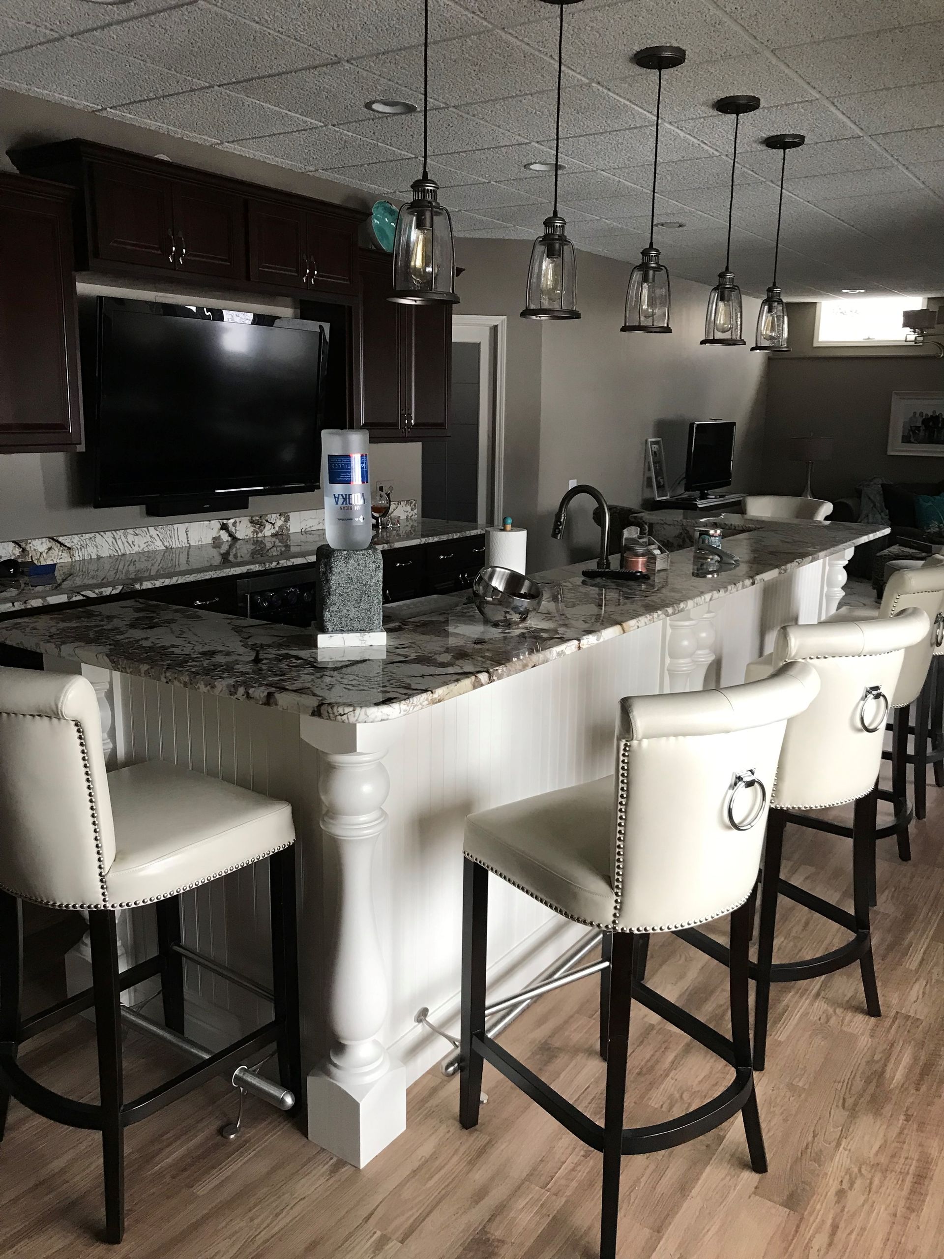 A Kitchen With a Bar and Stools and a Flat Screen TV — Clarkston, Michigan — Hidden Lake Cabinet & Trim LLC