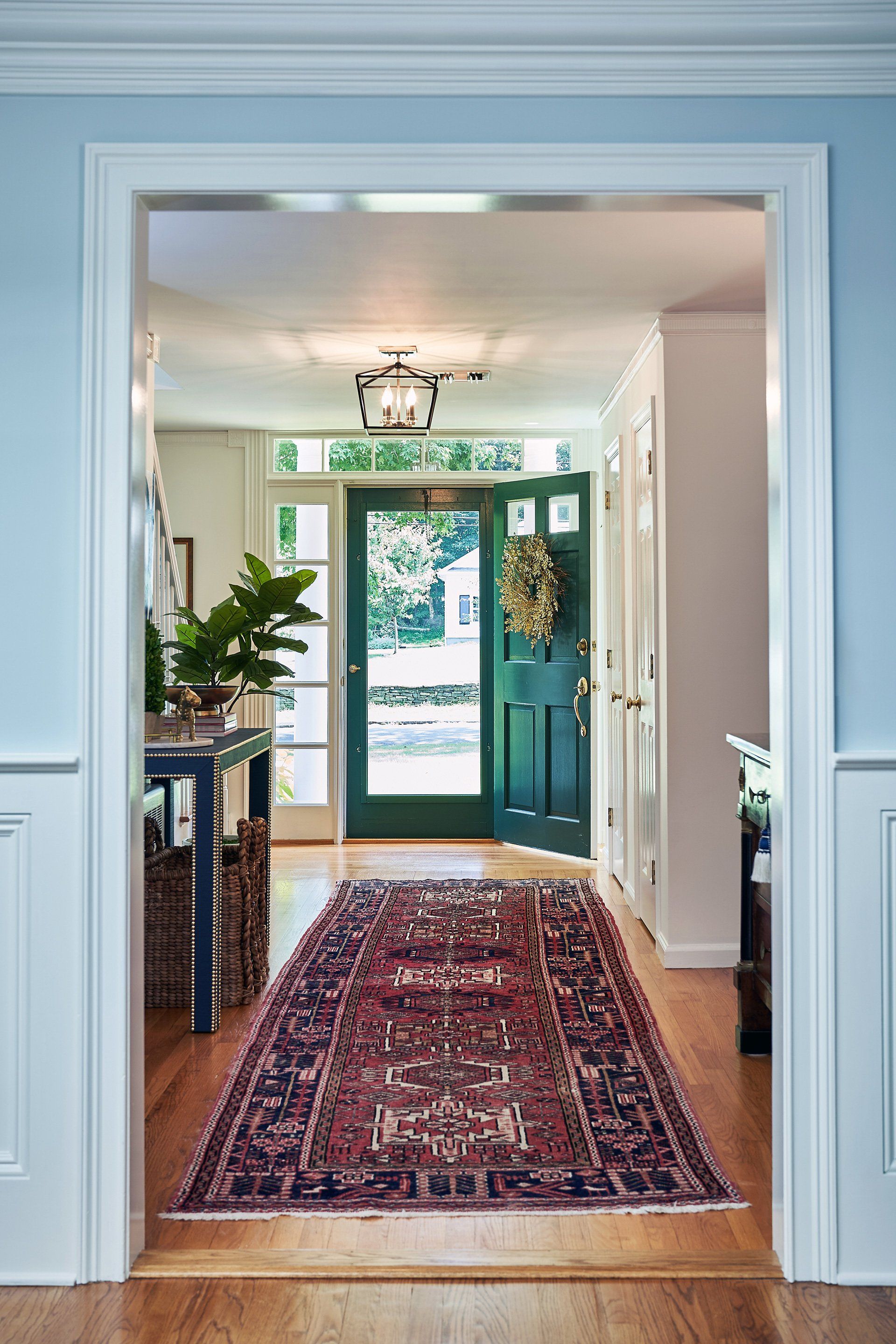 Hallway with a green door, red rug, and blue walls.