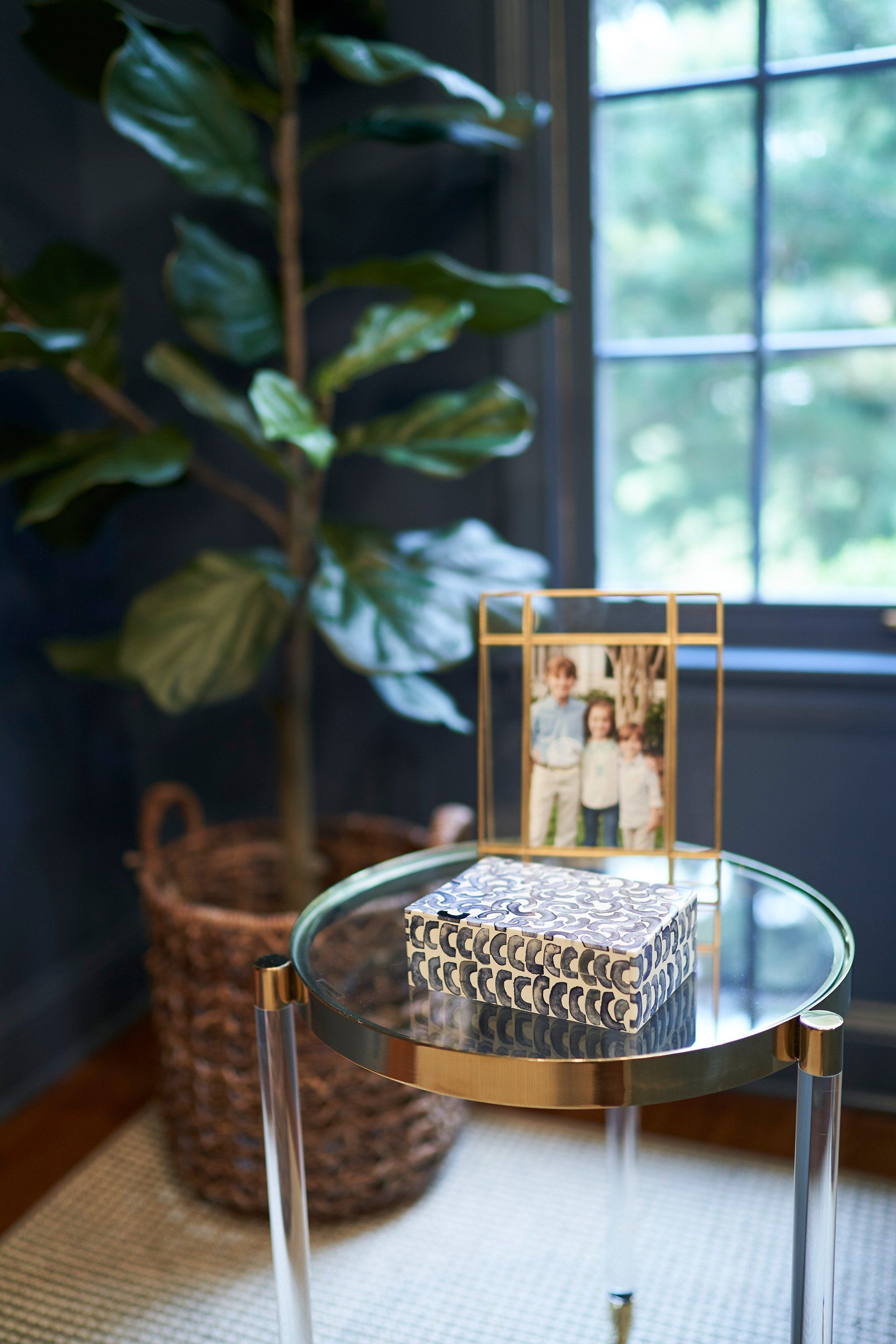 Clear table with photo, box, and plant in front of a window.