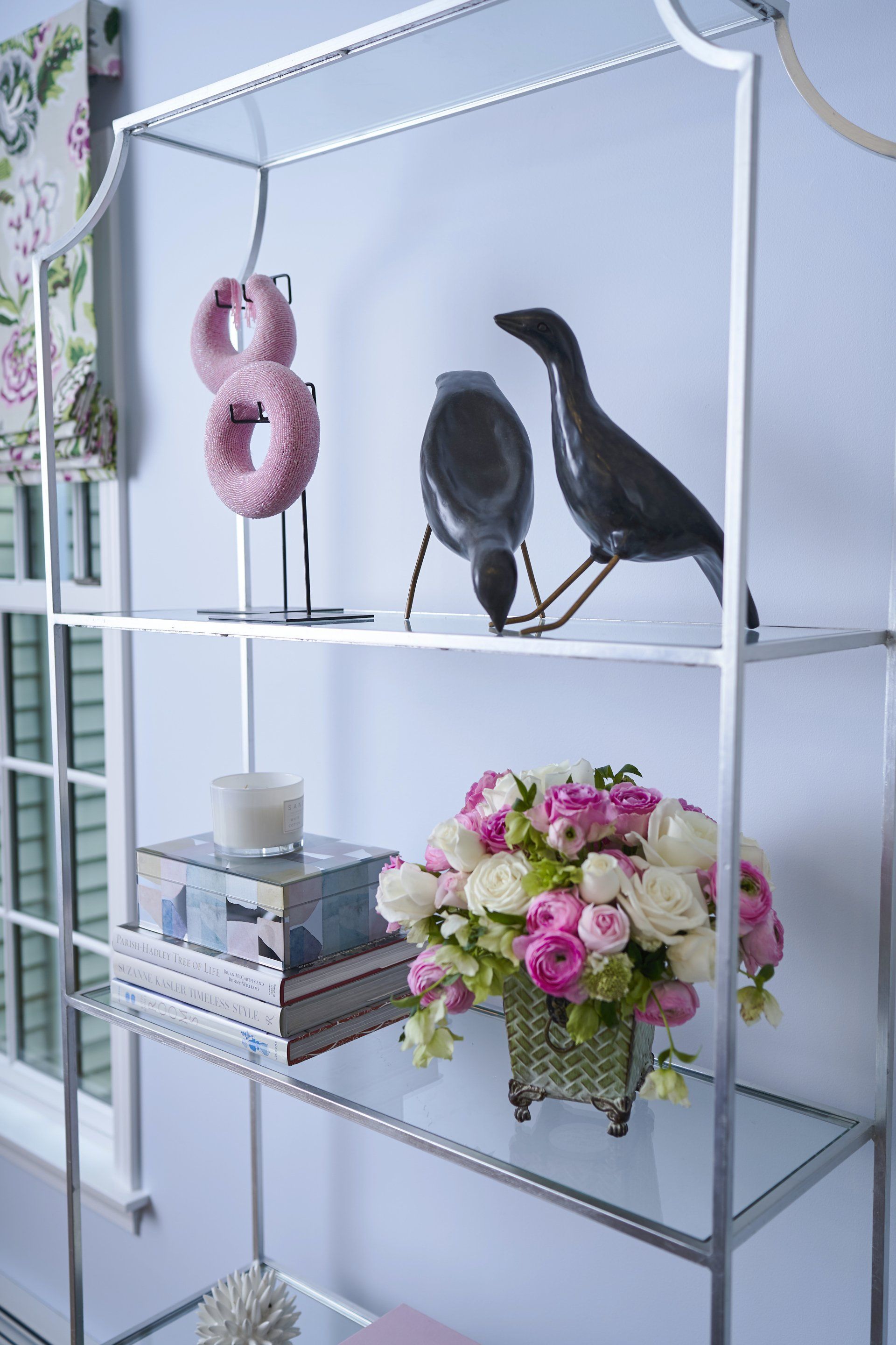 Silver shelf with decorative items: donuts, birds, flowers, books.