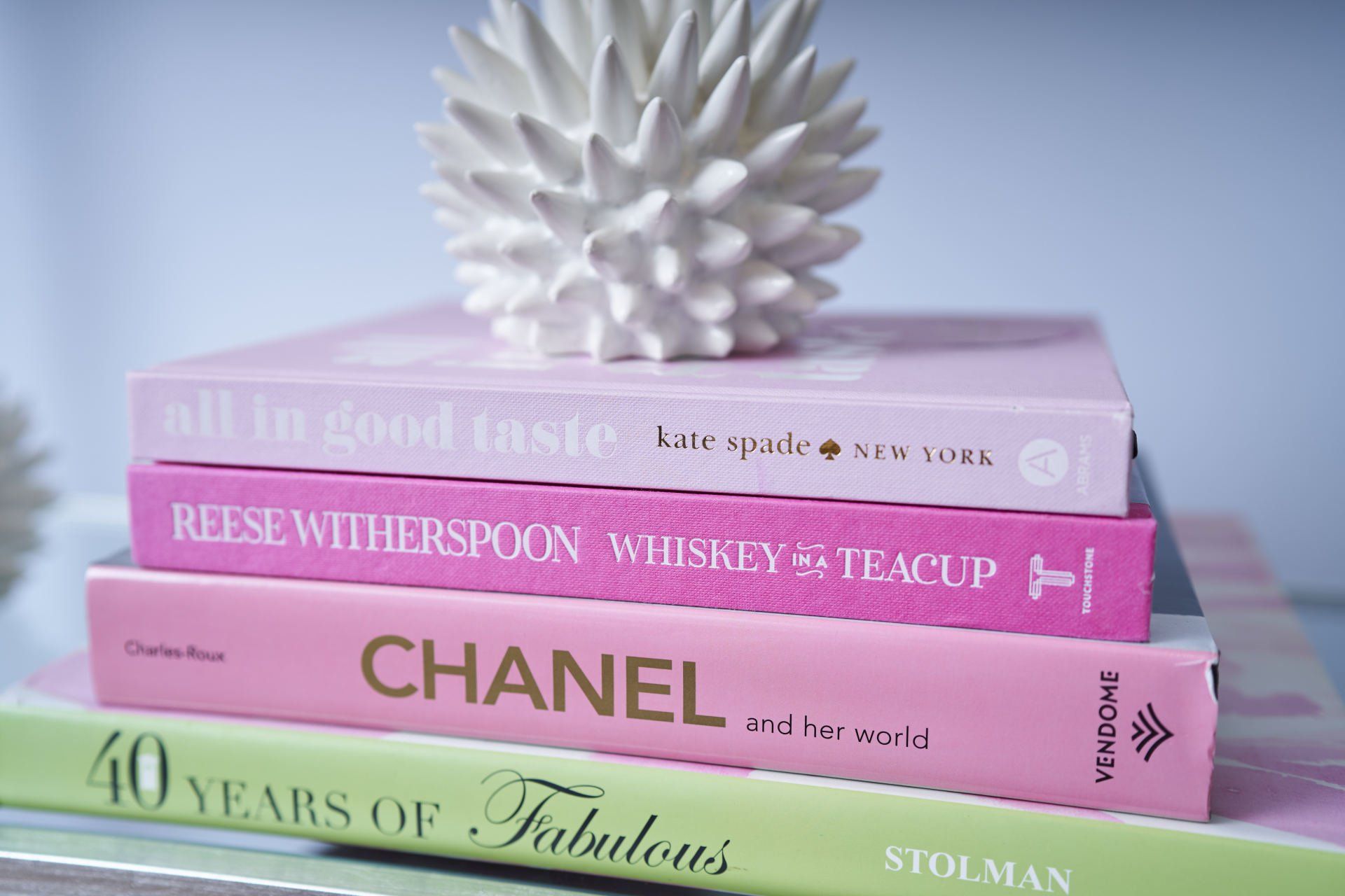 Stack of colorful books, topped with a white decorative object.