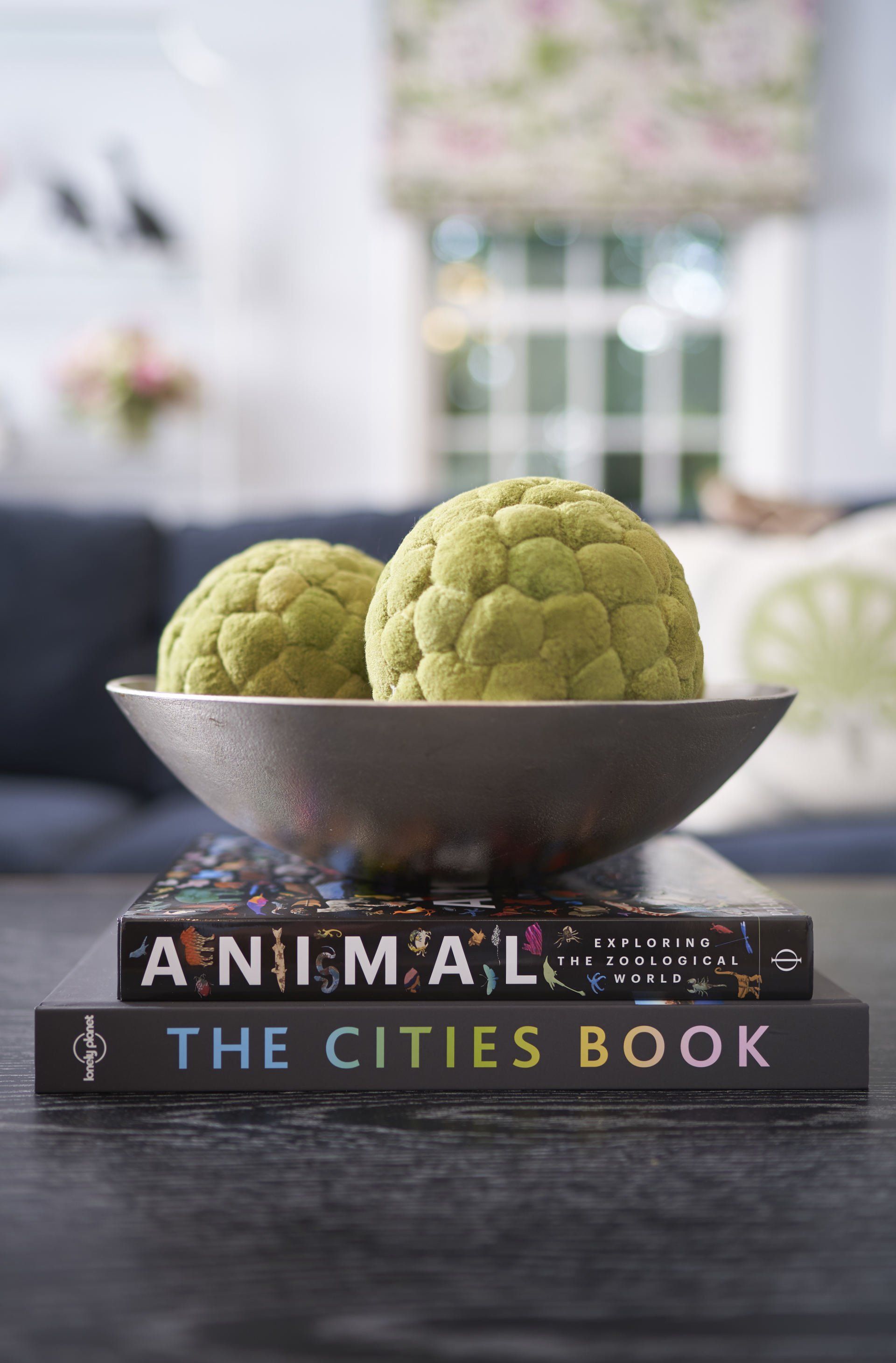 Bowl with green decorative spheres on books; interior setting.