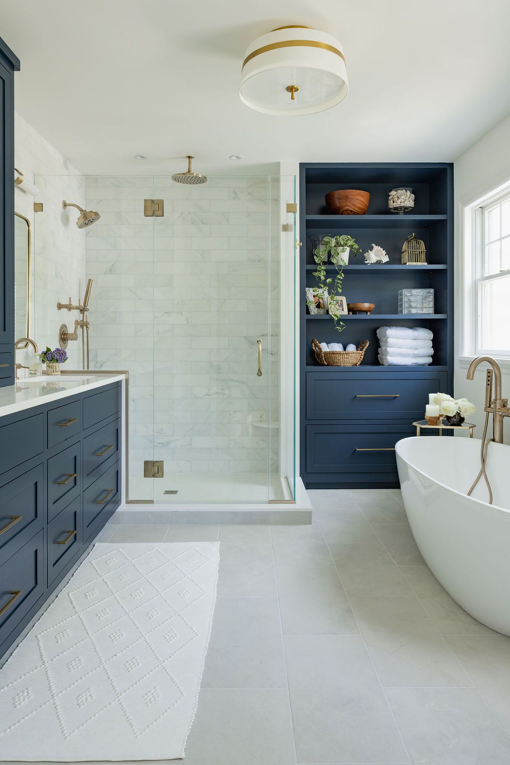 Elegant blue and white bathroom with a shower, bathtub, vanity, and built-in shelving.