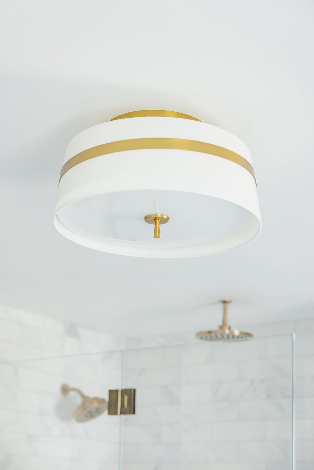 White and gold drum ceiling light fixture in a bathroom.