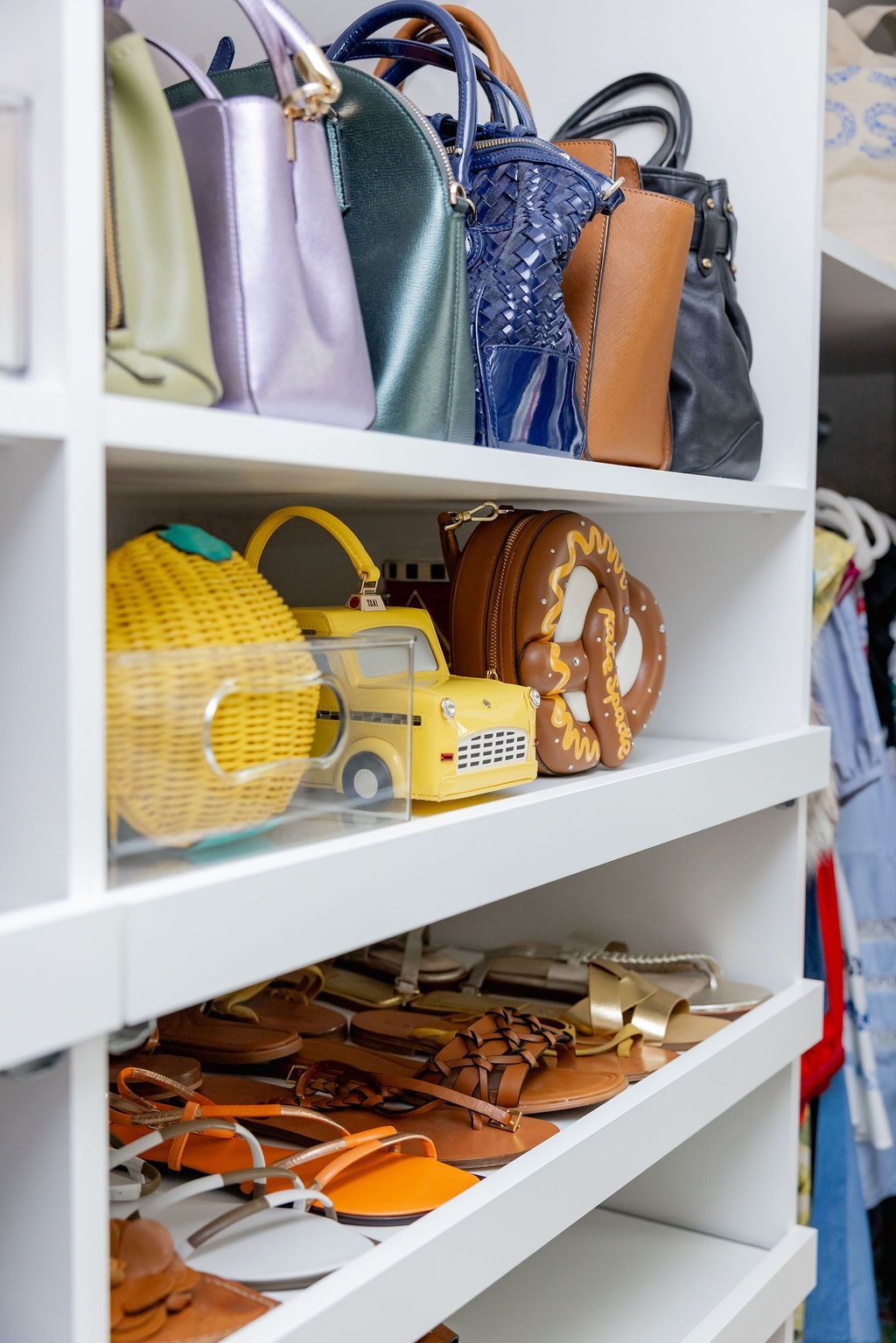 White closet shelves with handbags, clutches, and sandals.