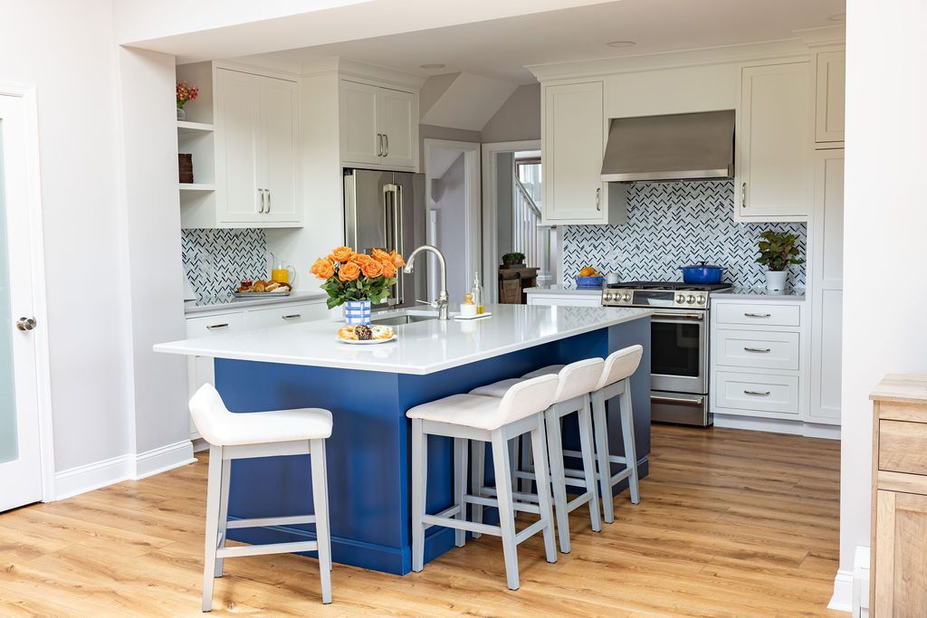 Modern kitchen with blue island and white cabinets. Wooden floor.
