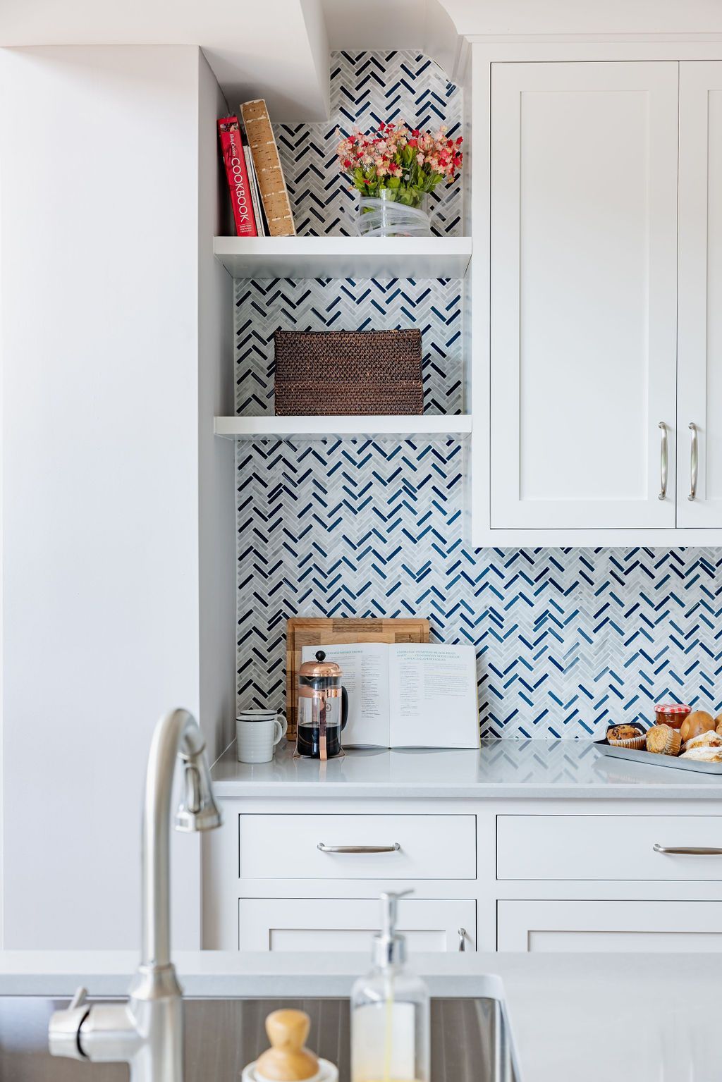 White kitchen with built-in shelves displaying decor against blue zig-zag pattern; sink in foreground.