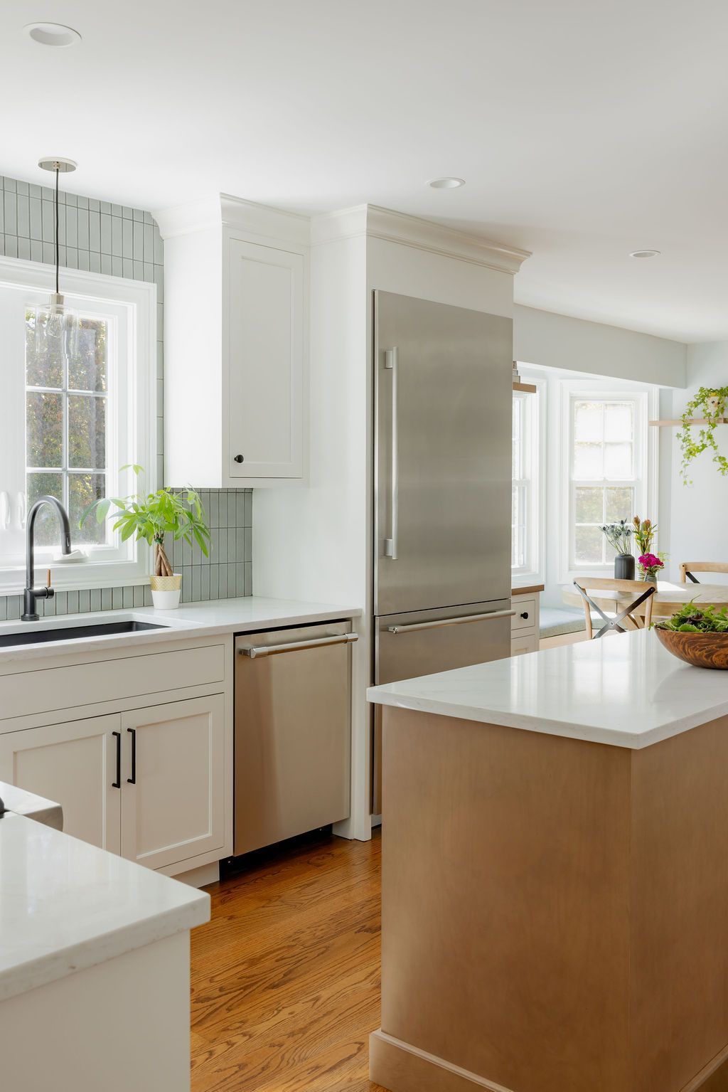 Modern kitchen with white cabinetry, stainless steel appliances, and a tan island.
