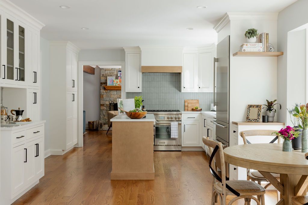 Bright kitchen with white cabinets, wood island, and round table.