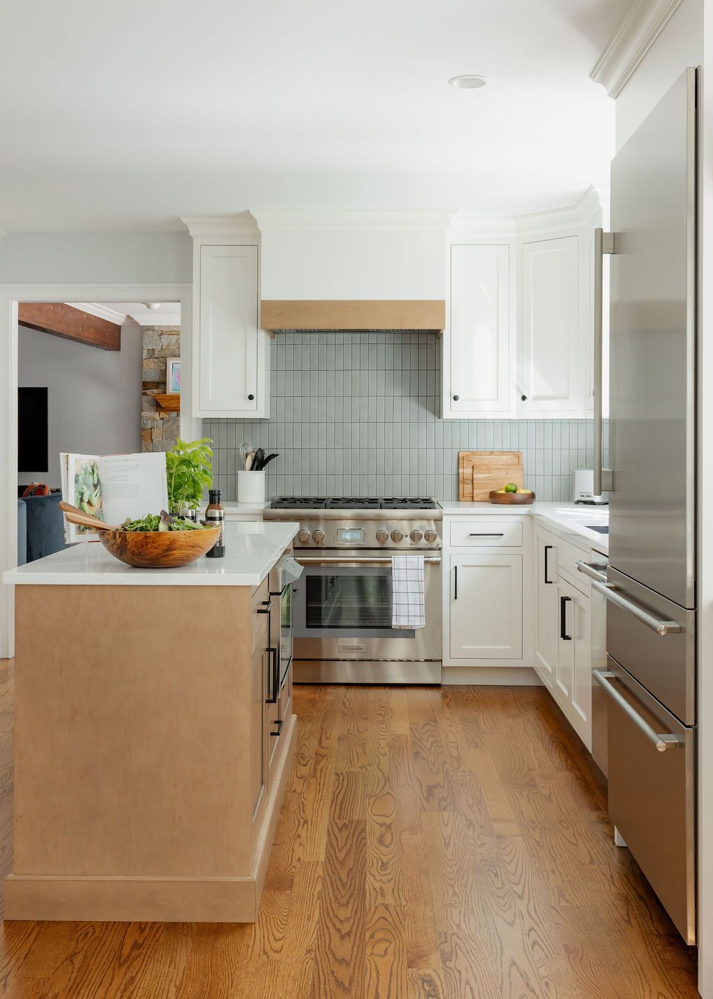 Modern kitchen with white cabinets, stainless steel appliances, and wood floors.