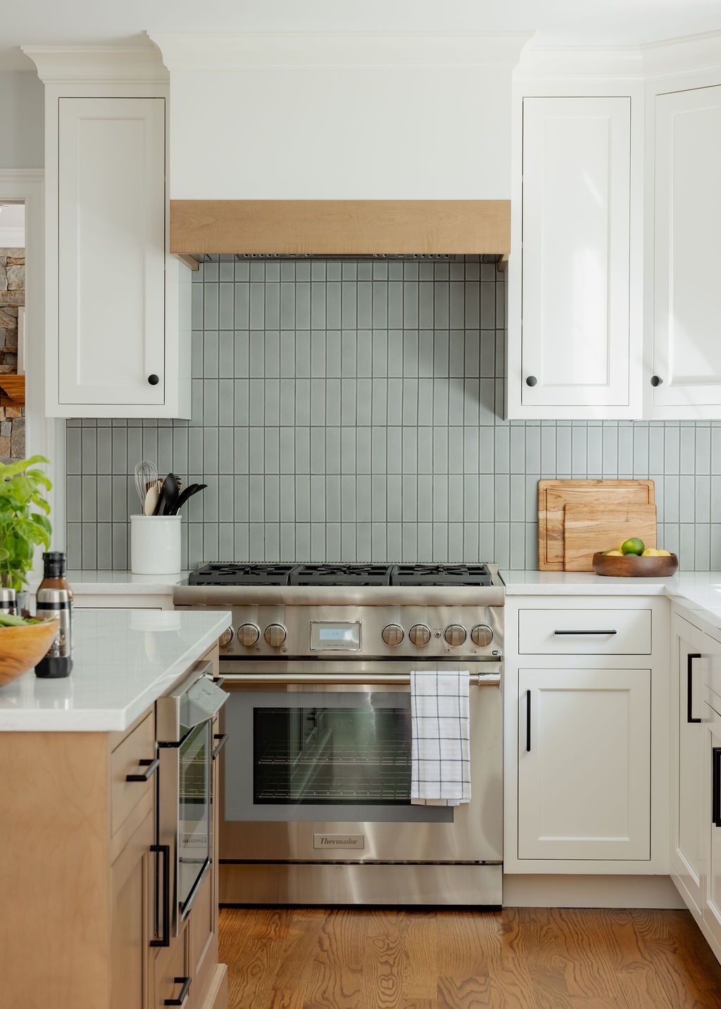 Kitchen with white cabinets, stainless steel stove, and blue-gray tiled backsplash.