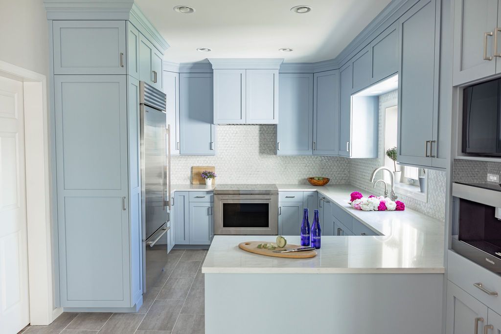 Light blue kitchen with white countertops and stainless steel appliances.