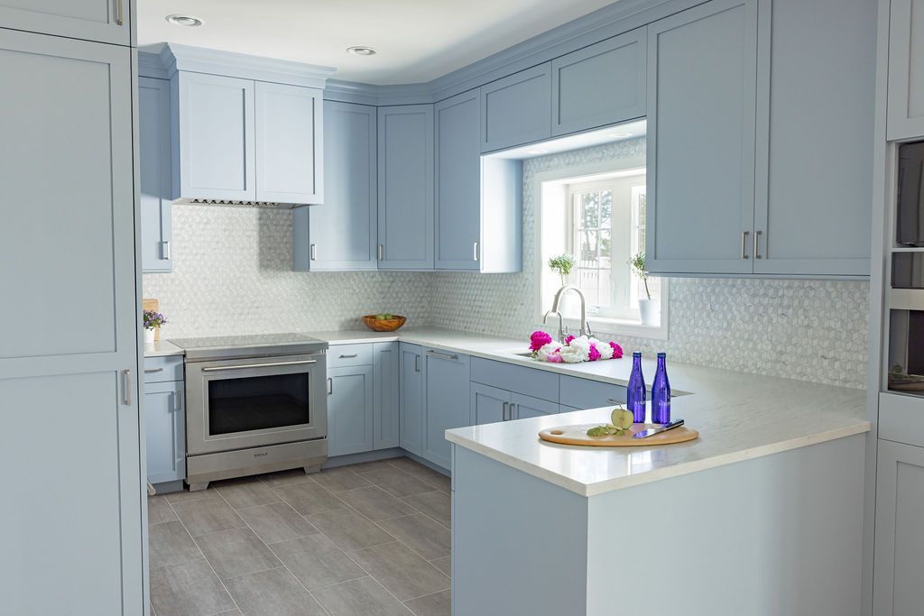 Light blue kitchen with white countertops and stainless steel appliances.