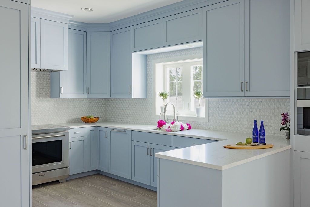 Blue kitchen with white countertops and white tiled backsplash.