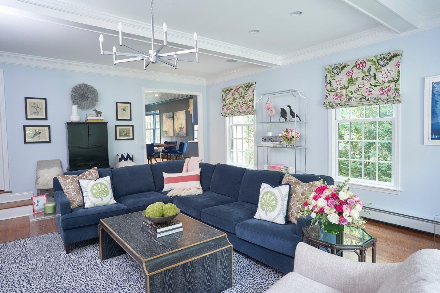 Living room with blue sectional sofa, floral curtains, and a dark cabinet.