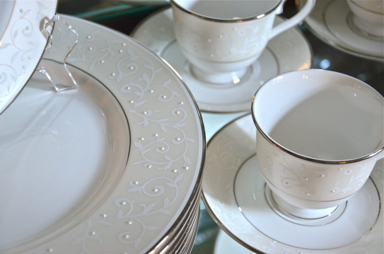 Elegant white china teacups and plates with silver trim and subtle embossed designs.