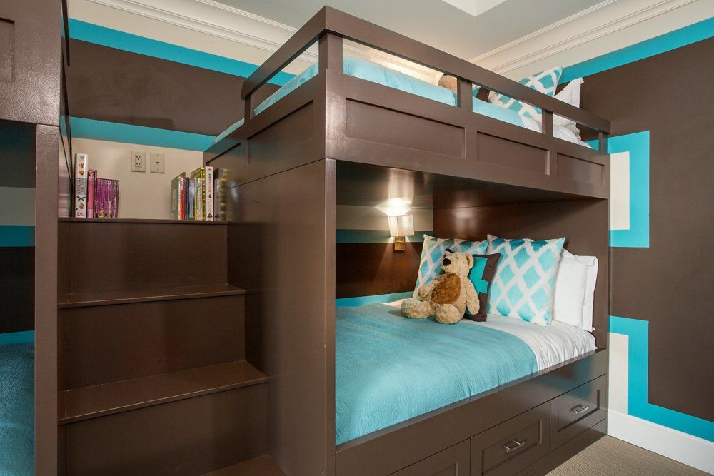 Brown and teal bunk beds in a child's bedroom. Includes stairs, shelves, and drawers.