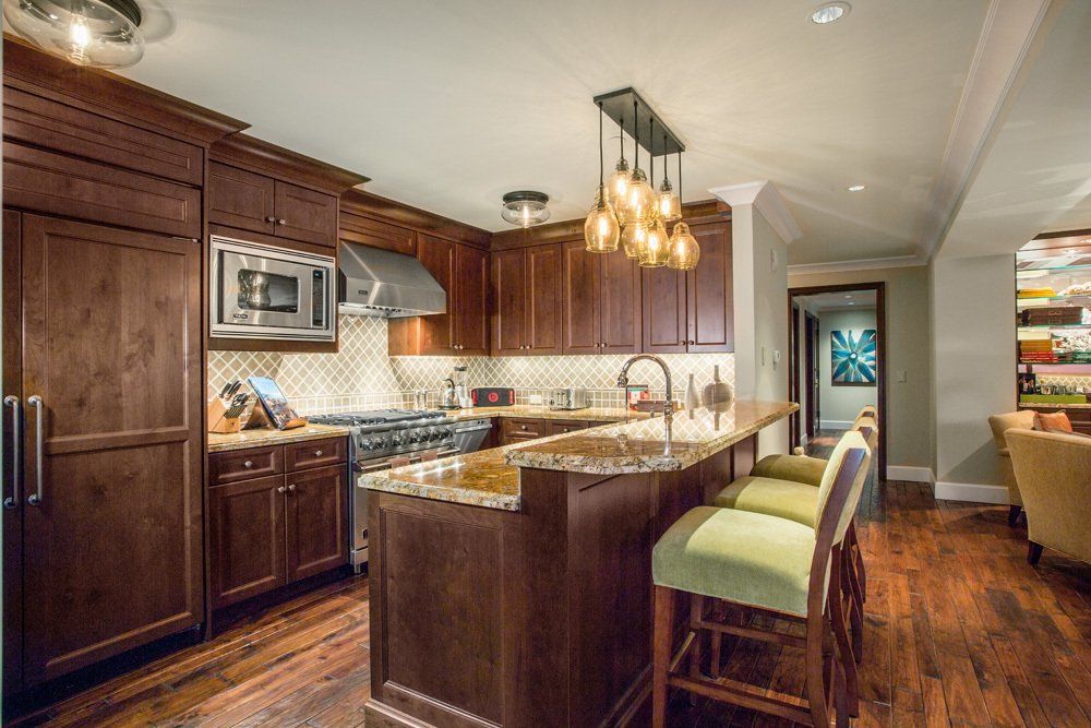 Kitchen with dark wood cabinets, granite countertops, and a breakfast bar with green stools.