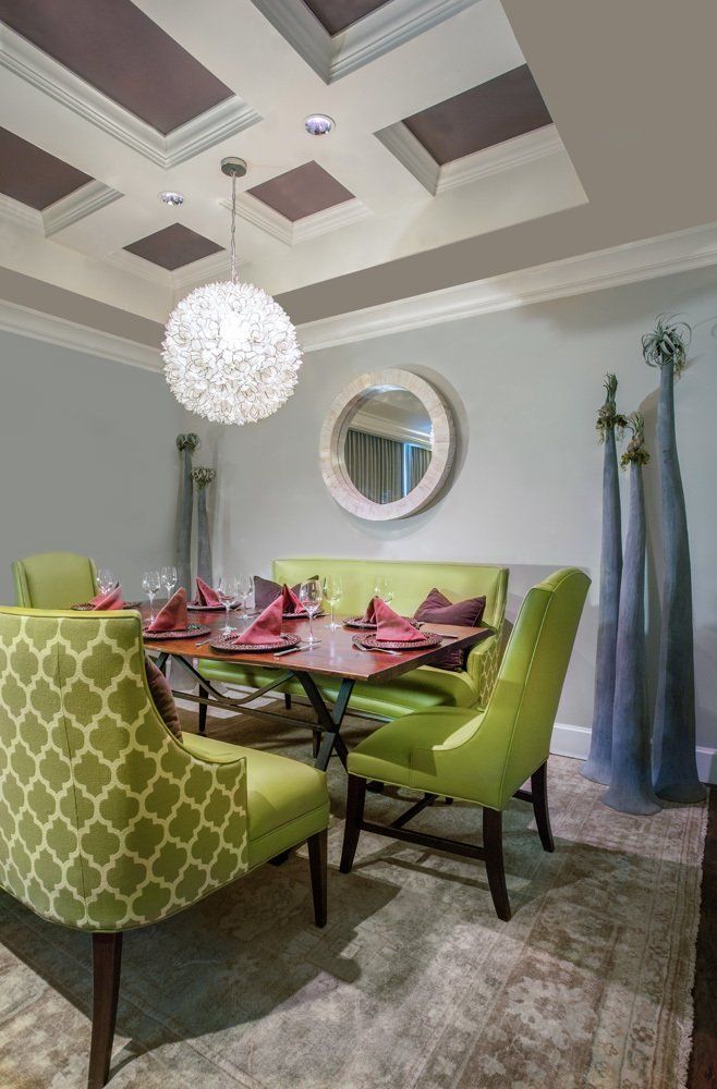 Dining room with green chairs, round table, and decorative ceiling.