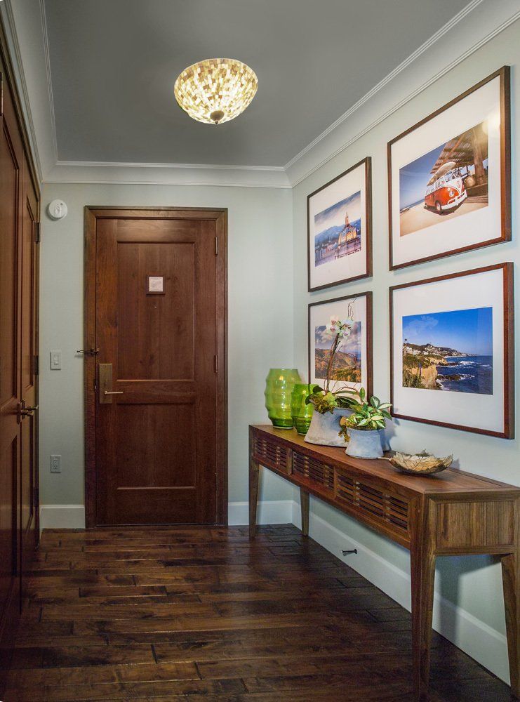Entryway with wooden door, console table, artwork, hardwood floor, and a decorative ceiling light.