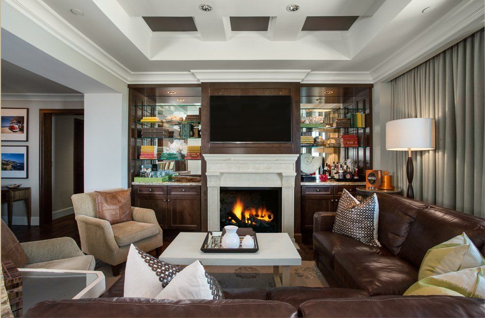 Cozy living room with fireplace, built-in shelves, leather sofa, and armchairs.