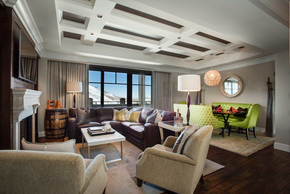 Living room with brown leather sofa, armchairs, dining area, snow view through window.