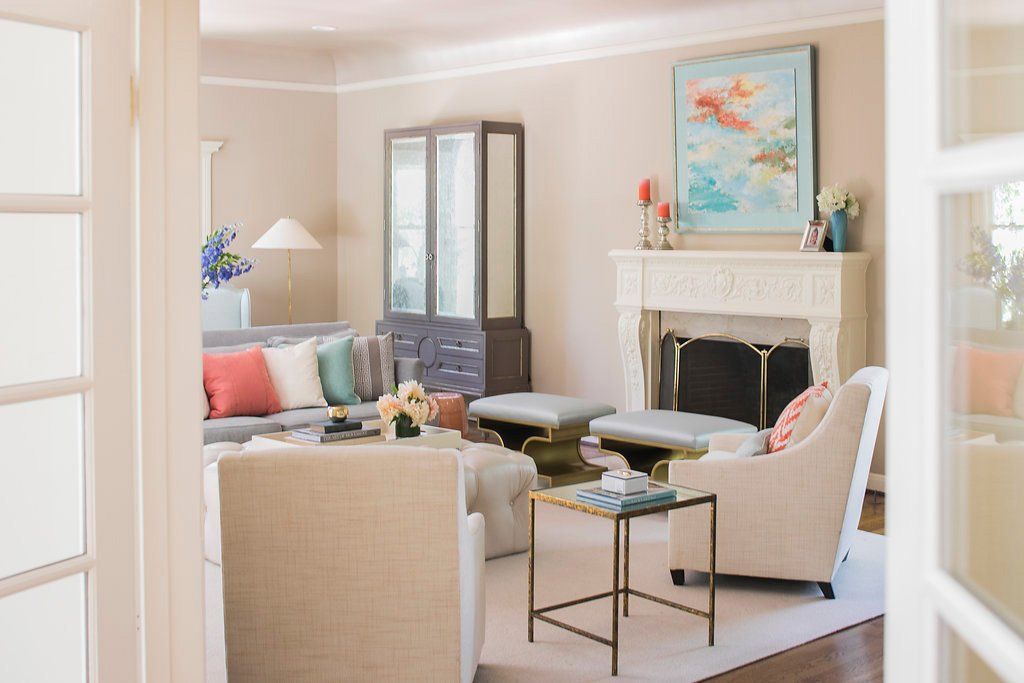 Living room with a fireplace, sofa, chairs, and artwork, in neutral tones.