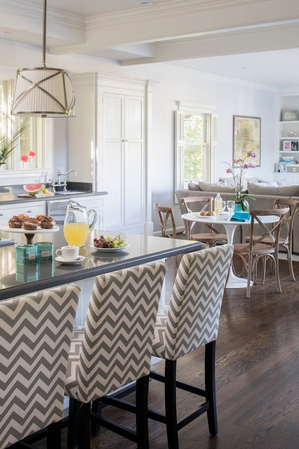 Kitchen with chevron-patterned bar stools, dark countertop, and dining area with a round table.