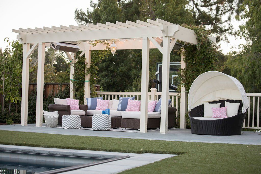 Outdoor patio with seating under a pergola, including a couch and a round daybed.