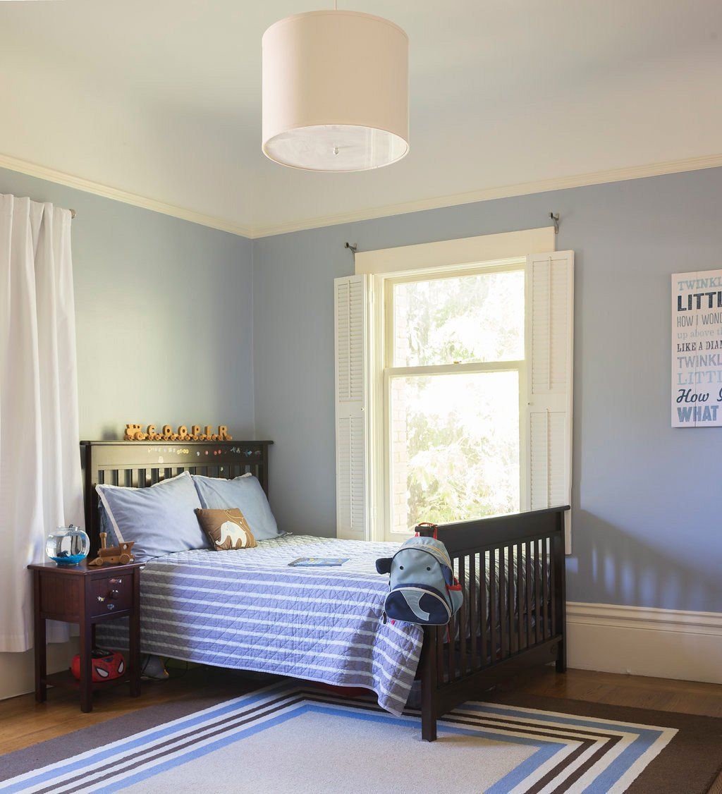 Bedroom with blue walls, a bed, window, and a drum-shaped light fixture.
