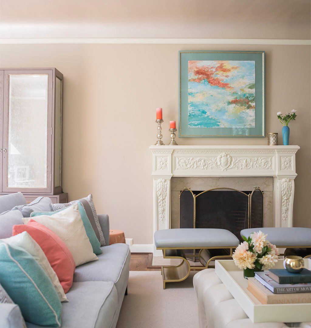 Living room with fireplace, gray sofa with colorful pillows, artwork, and neutral walls.
