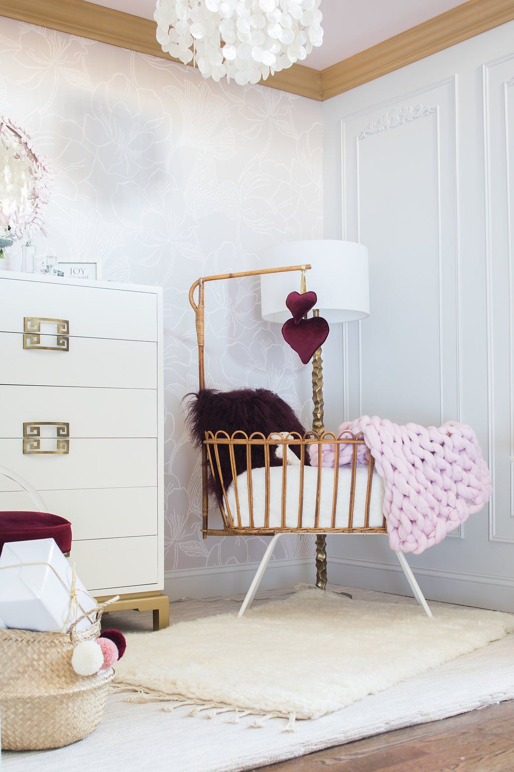 Baby's nursery with white dresser, crib, pink blanket, and a decorative mobile.