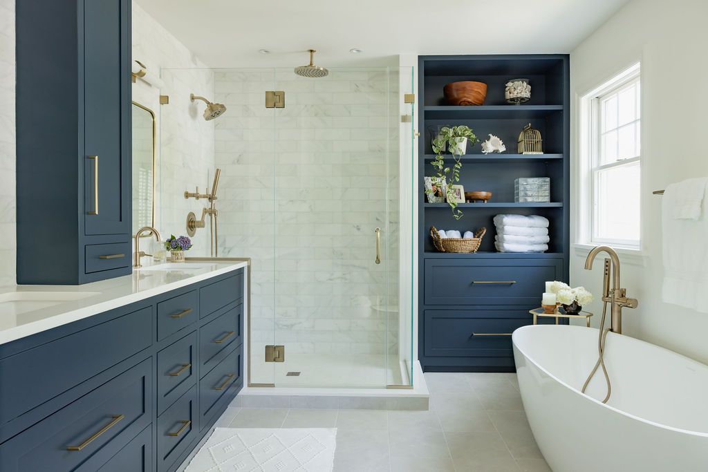 Navy blue bathroom with double vanity, shower, and freestanding tub.