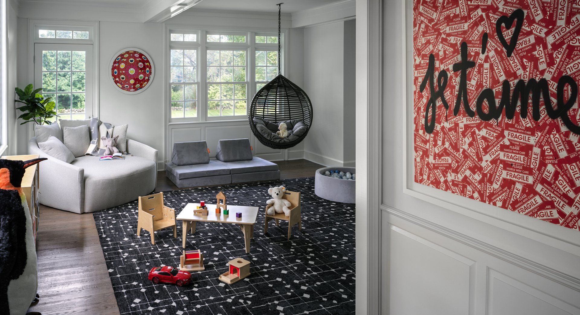 Playroom with white walls, black and white rug, and hanging chair; featuring children's furniture and 