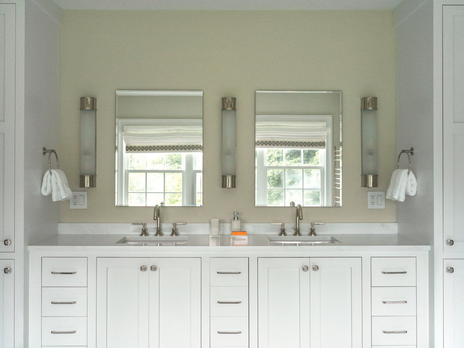 White double vanity with two mirrors, sconces, and towels in a bathroom.