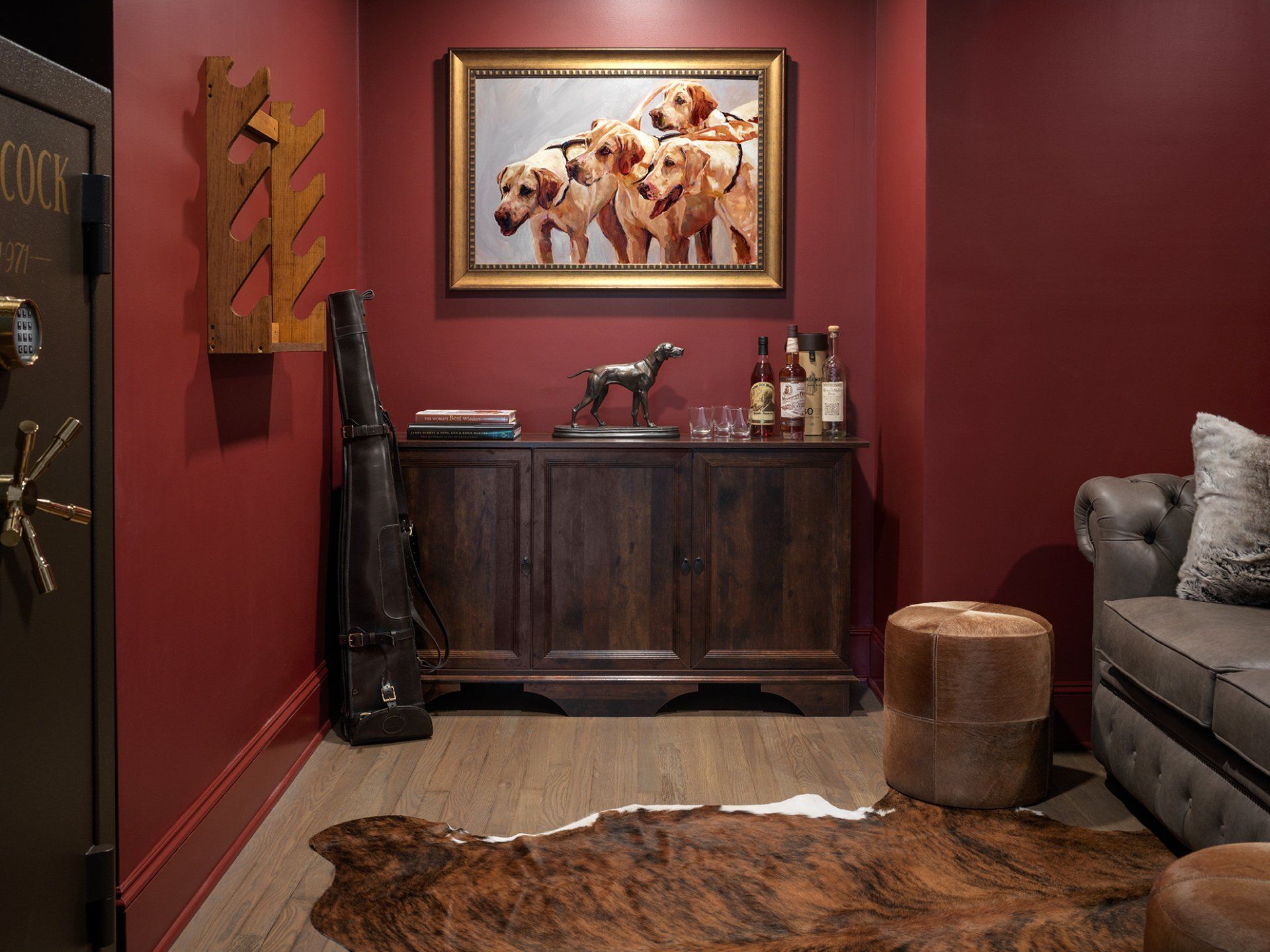 Burgundy room with wooden cabinet, dog painting, cowhide rug, and safe door.