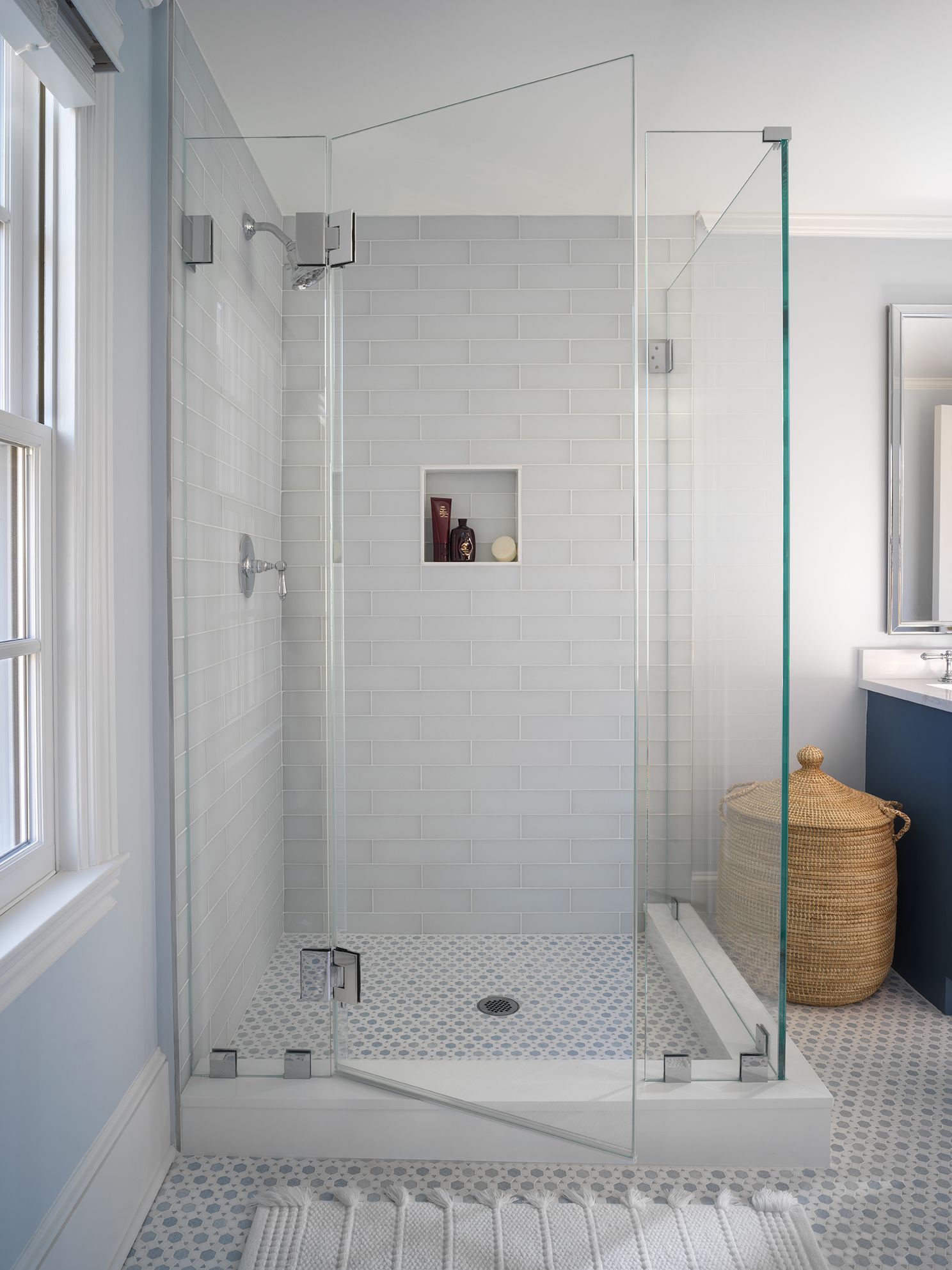 Modern shower with glass walls, white subway tile, and patterned floor.