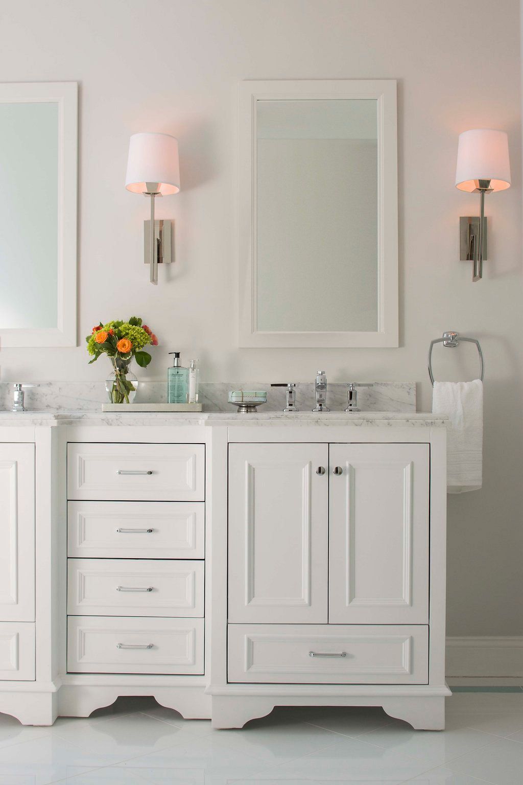White bathroom vanity with two mirrors and sconce lighting.