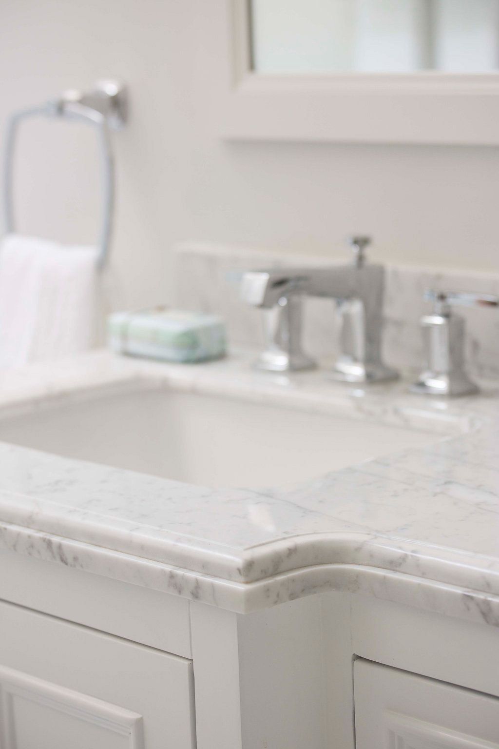 White marble bathroom vanity with chrome faucet and soap dish.